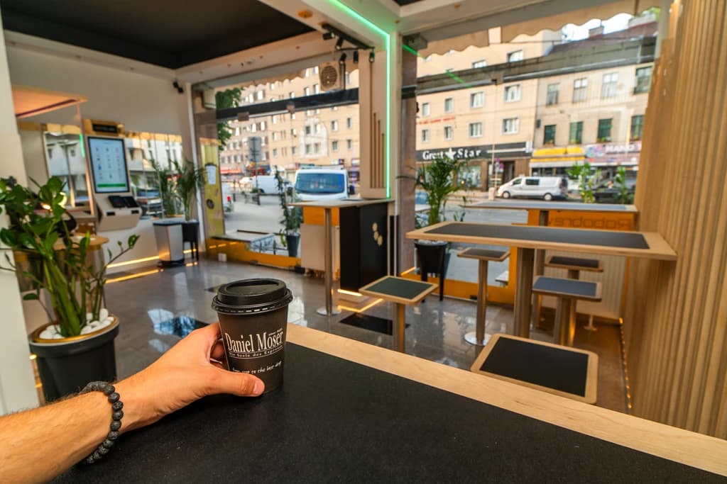 Customer hand holding a takeaway coffee inside the shop